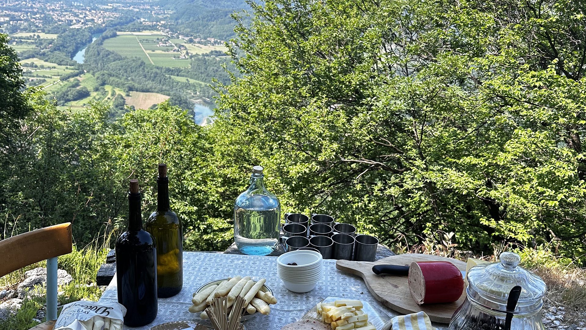 La degustazione panoramica: vino, formaggi e pane su un tavolo affacciato sulla valle