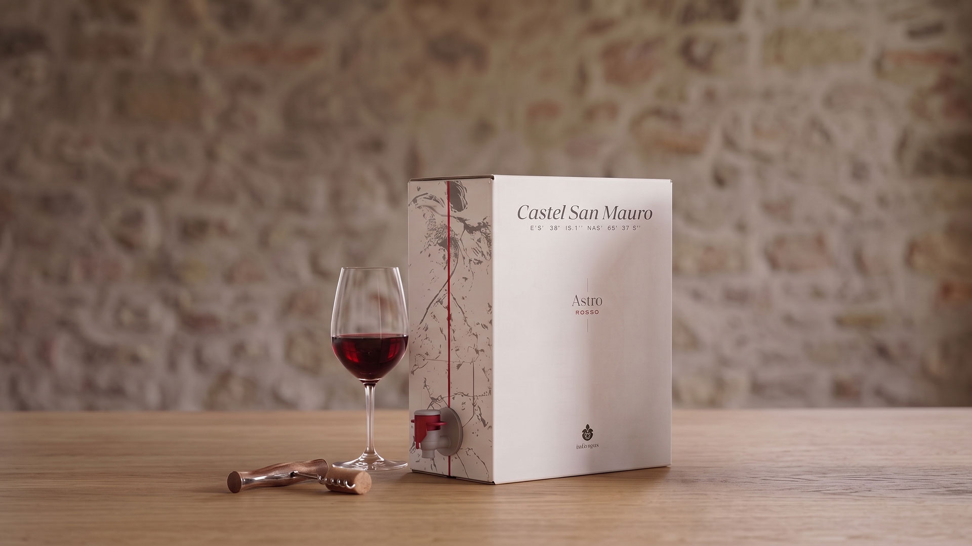 Il bag in box Astro Rosso su un tavolo di legno, con un calice di vino rosso e un cavatappi
