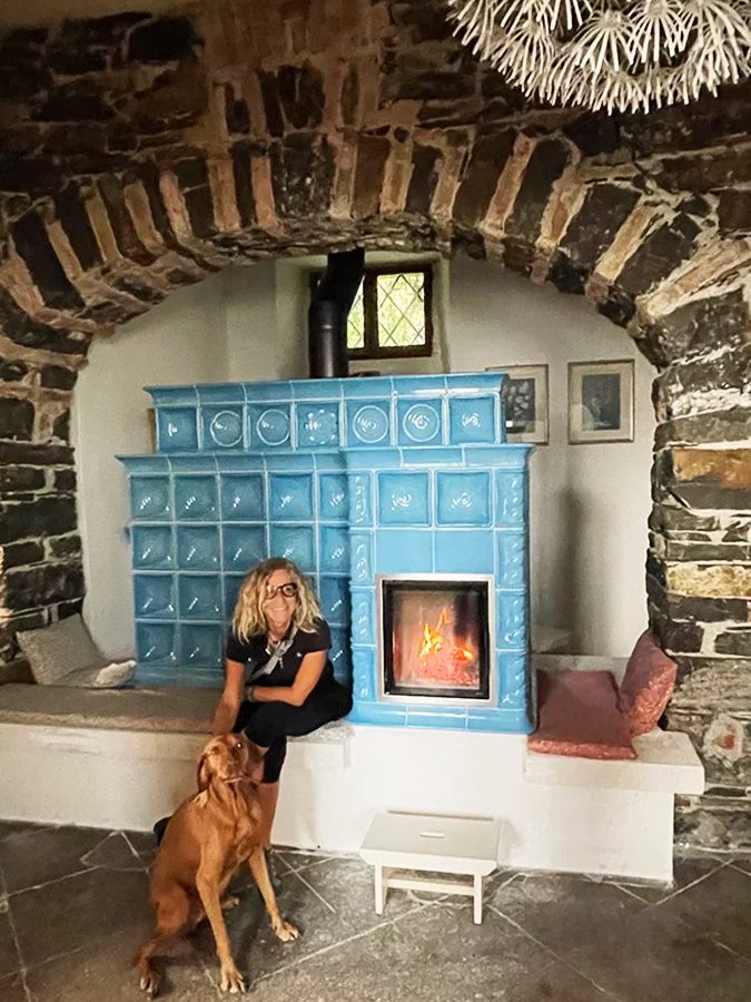 La grande Stube in maiolica azzurra dentro l’arco di pietra della sala colazioni, con il fuoco acceso