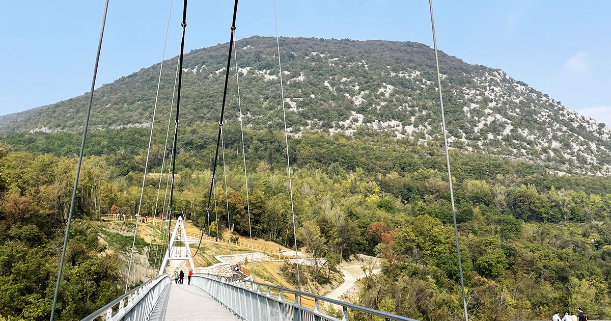 Una passerella sospesa, con il Monte Sabotino sullo sfondo